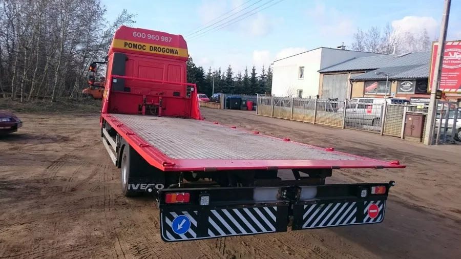 Czerwona ciężarówka z platformą jest zaparkowana na polnej drodze - holowniki, ciężarówka.