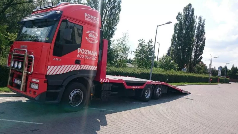Czerwona ciężarówka holowniki zaparkowana na parkingu.