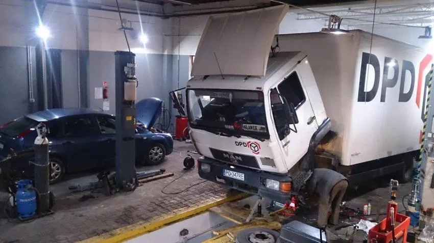 W garażu trwają prace nad ciężarówką.