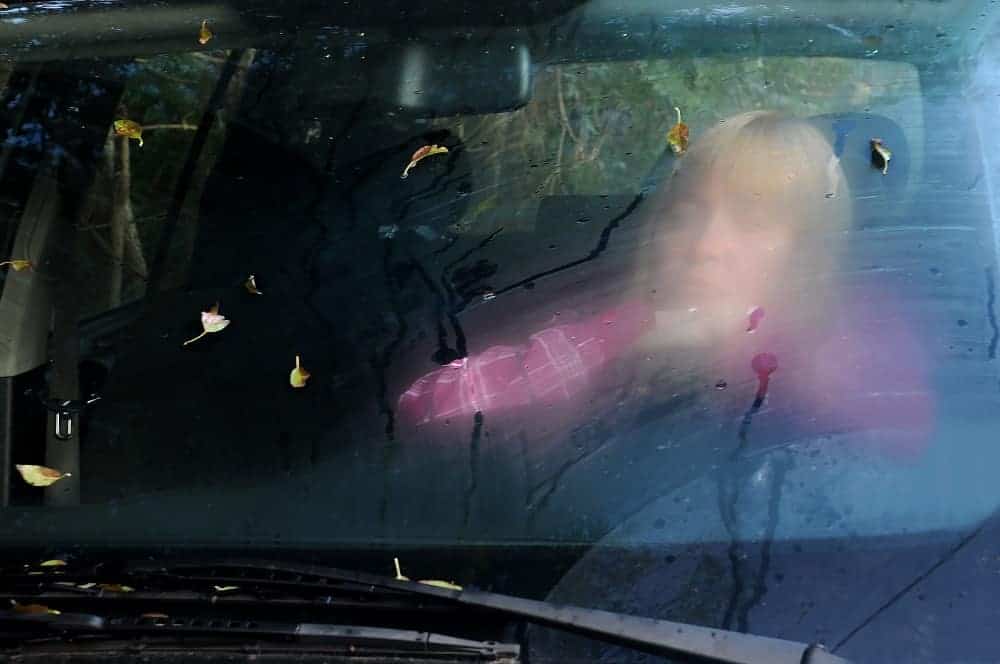 Kobieta w samochodzie patrząca przez okno.