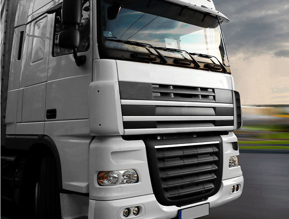 Biała ciężarówka jadąca drogą.